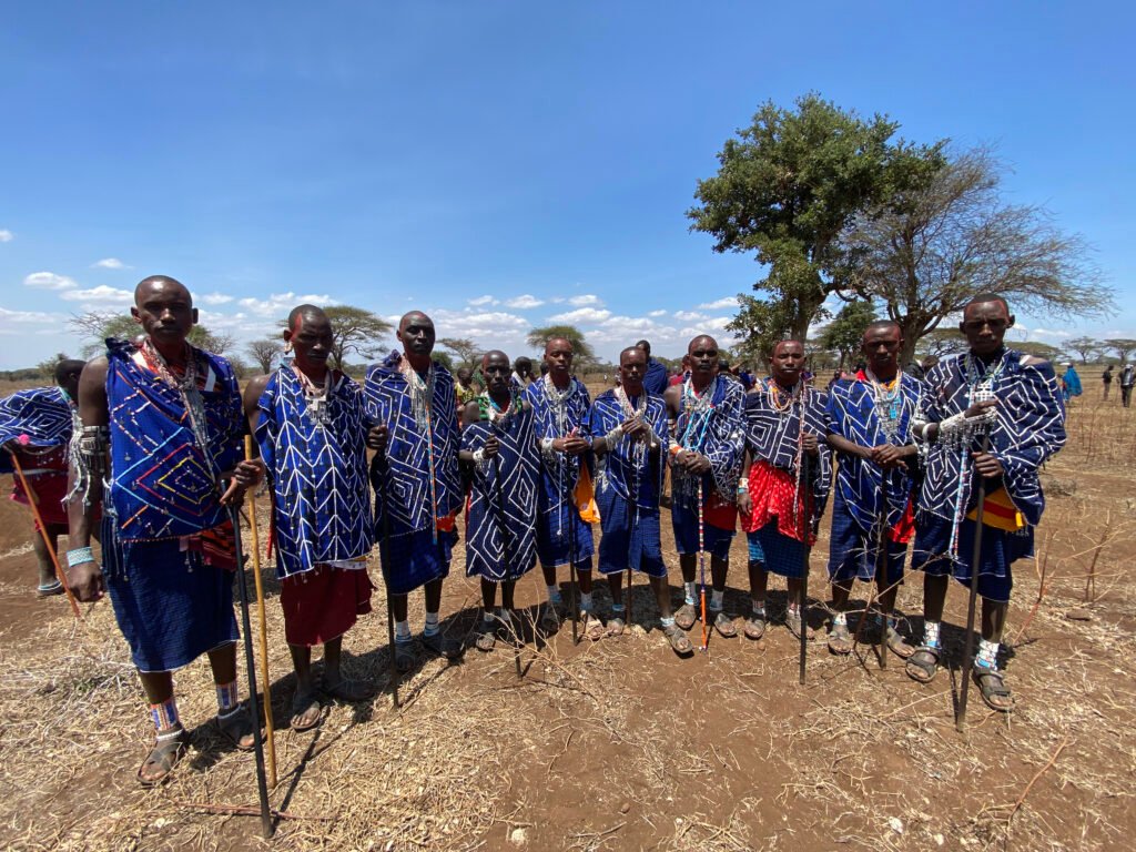 Maasai Men: In the Maasai tradition, men undergo different social stages: childhood, young adulthood (Moranism), adult (post-Moranism), and old age. Moranism starts immediately after circumcision. Moran are the warriors expected to protect the people and cattle.   In this stage, men live isolated from community life and live very closely with their fellow Moran.  A Moran must not eat, drink, sleep, sing, fight, sell or buy cattle, or even bathe alone but must be in the company of other Moran.   During events like this emuta, Moran are given an isolated place in the bush to cook and eat their food. In these places, women are not allowed to go.  If they do, the food will be left since it is taboo to eat food seen by women.